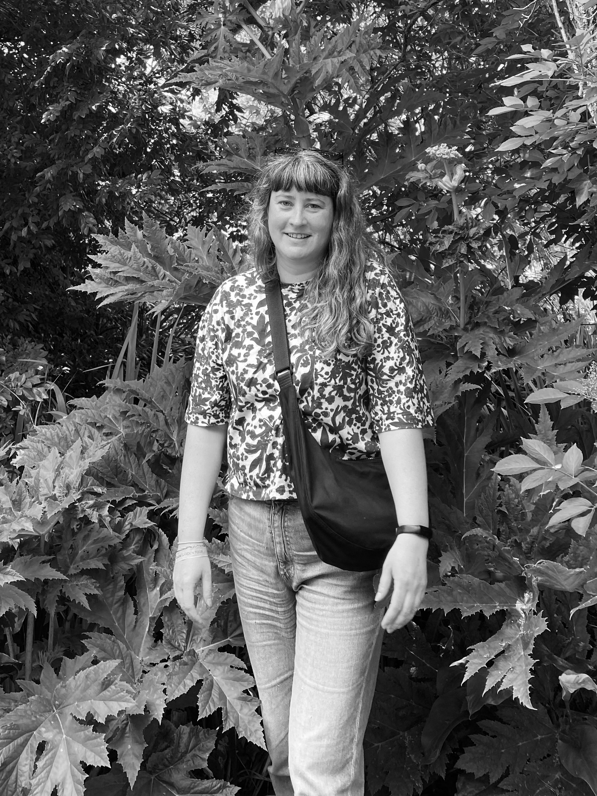 Adrianne Reid, Wellington garden designer, standing among lush garden foliage